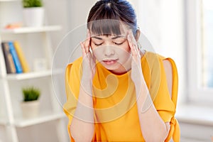 Tired asian woman suffering from headache at home