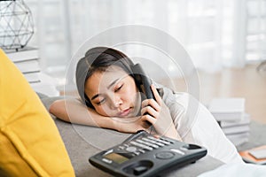 Tired Asian woman use phone and drowsy due to work on holidays. photo