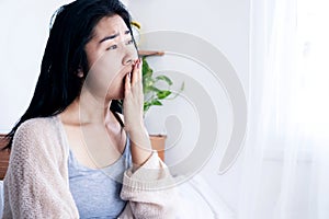 Tired Asian woman yawning  after wake up in bed feeling sleepy in the morning , sleepless or insomnia concept