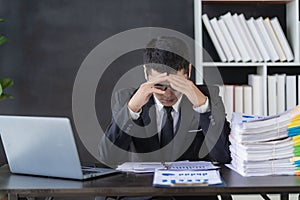 Tired asian young businessman with stacks of paperwork. Busy work, overworked,