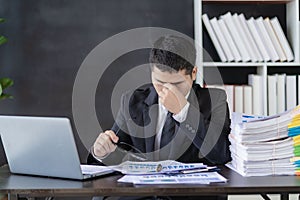 Tired asian young businessman with stacks of paperwork. Busy work, overworked,