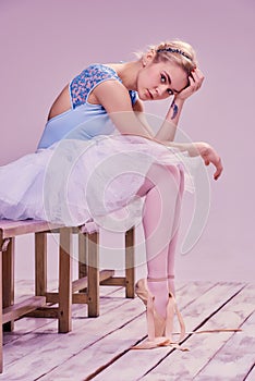 Tired ballet dancer sitting on the wooden floor