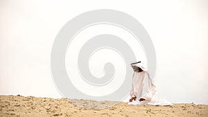 Tired Bedouin kneeling in desert, exhausted and lost, overcoming difficulties