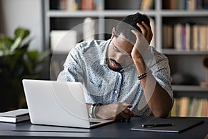 Tired bored african employee falling asleep sitting at work desk