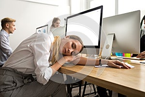 Tired or bored female employee lying asleep at office workplace photo