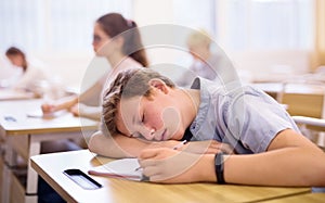 Tired bored teenage school boy sleeping at desk