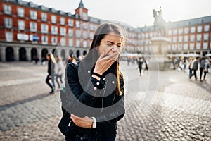 Tired bored woman yawning in main Plaza Major square of Madrid,Spain.Sightseeing female tourist covering moutht.Lack of slee