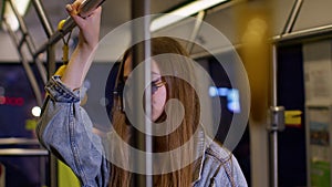 Tired, bored young woman standing alone in bus transport after hard work day and falling asleep