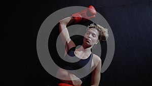 Tired boxer woman is lying down after hard training, wearing sport clothes and red boxing gloves. Caucasian female