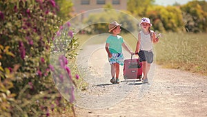 Tired boy and girl hitchhiking at the road with a suitcase