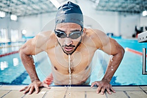 Tired, breathing and man swimming for fitness, training and race in a stadium pool. Strong, sports and face of an