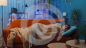 Tired brunette young woman lying down in bed taking a rest at home, napping falling asleep on sofa