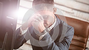 Tired business man at workplace in office holding his head on hands. Sleepy worker early in the morning after late night work. Ove