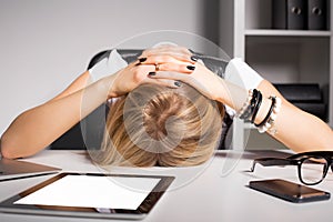 Tired business woman resting her head on desk