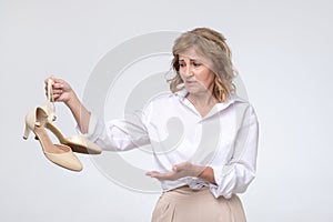 Tired business woman in white shirt holding uncomfortable high heels
