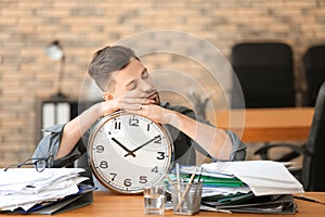 Tired businessman with clock in office. Time management concept