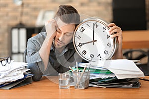 Tired businessman with clock in office. Time management concept