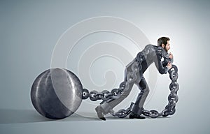 Tired businessman dragging heavy chains