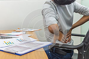 Tired businessman having spinal pain stretching his back at office