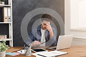 Tired businessman with laptop in modern white