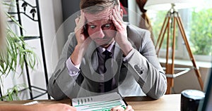 A tired businessman in the office holds on his head, close-up