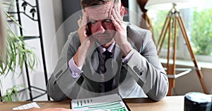 A tired businessman in the office holds on his head, close-up