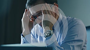 Tired businessman sitting on a laptop in office at night