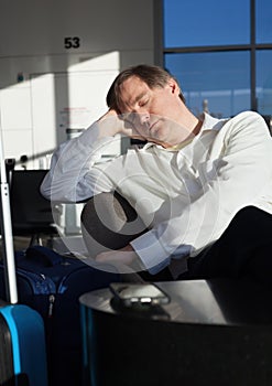 Tired businessman sleeping in airport terminal with luggage