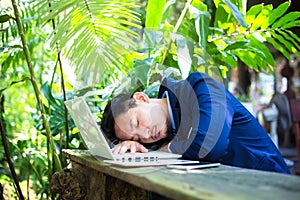 Tired businessman sleeping over a laptop in a desk at coffee shop