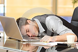 Tired businessman sleeping over a laptop at job photo