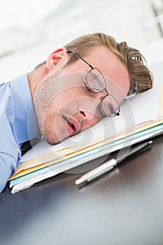 Tired businessman with stack of files on desk