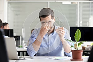 Tired businessman taking off glasses to relieve dry irritated ey