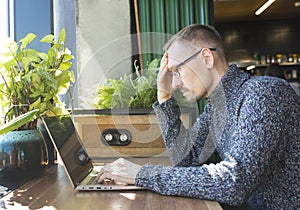 Tired businessman is trying to solve problem with work. A Man sits with serious face in front of computer.