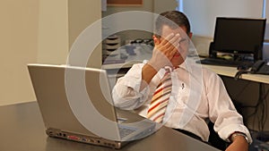 Tired businessman using laptop in office