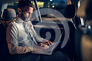 Tired businessman working late in car on laptop