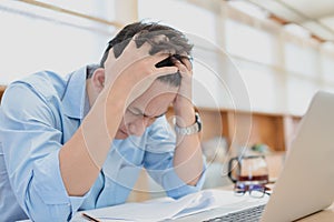 Tired businessman at workplace in office holding his headache or angry. Overworking, making mistake, stress, termination, fail,