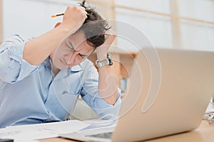 Tired businessman at workplace in office holding his headache or angry. Overworking, making mistake, stress, termination, fail,