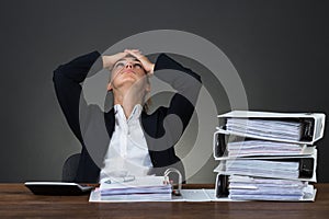 Tired Businesswoman With Hands On Head At Desk