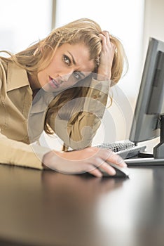 Tired Businesswoman Looking Away While Sitting At Computer Desk