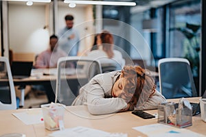 Tired businesswoman sleeping at desk after hard day at work.