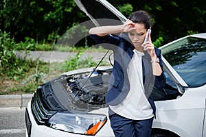 tired businesswoman talking by smartphone near broken car