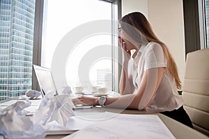 Tired businesswoman yawning at desk with laptop