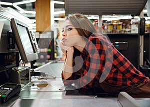 Tired cashier lady lies on workspace in supermarket shop