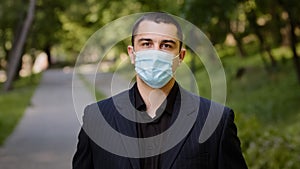Tired caucasian businessman takes off medical face mask protective respirator exhausted man guy stands in city park