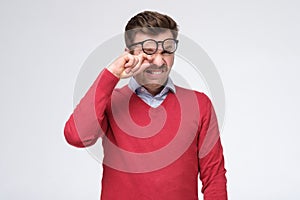 Tired caucasian man suffer from eyesight problems or blurry vision rubbing his eye