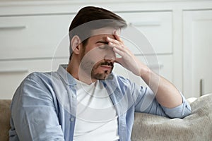 Tired Caucasian man suffer from headache at home