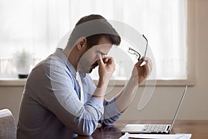 Tired Caucasian man suffer from headache working on computer