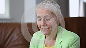 Tired Caucasian middle aged woman rubbing eyes sitting indoors having head ache and looking at camera smiling. Portrait