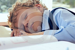 Tired Caucasian schoolboy sleeping in classroom at school. Ð¡oncept of heavy workload in school.