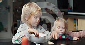 Tired child boy after school eating with his toddler sister on living room